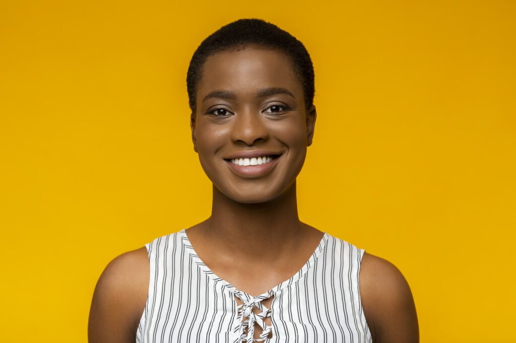 Portrait of smiling black woman on yellow background
