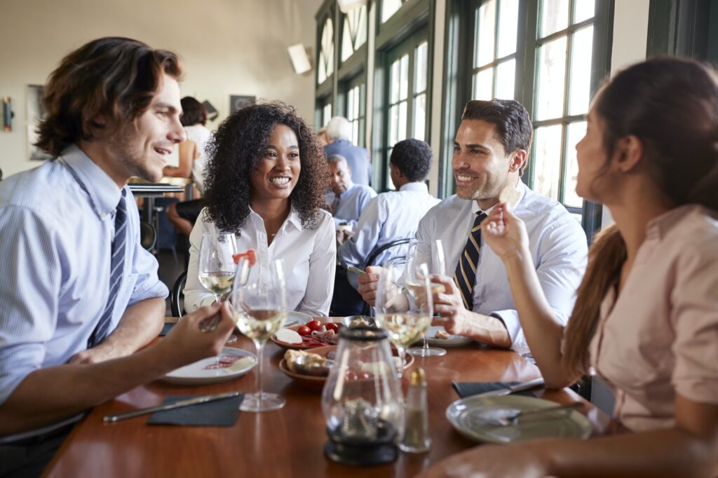 Business Colleagues Sitting Around Restaurant Table Enjoying Meal Together