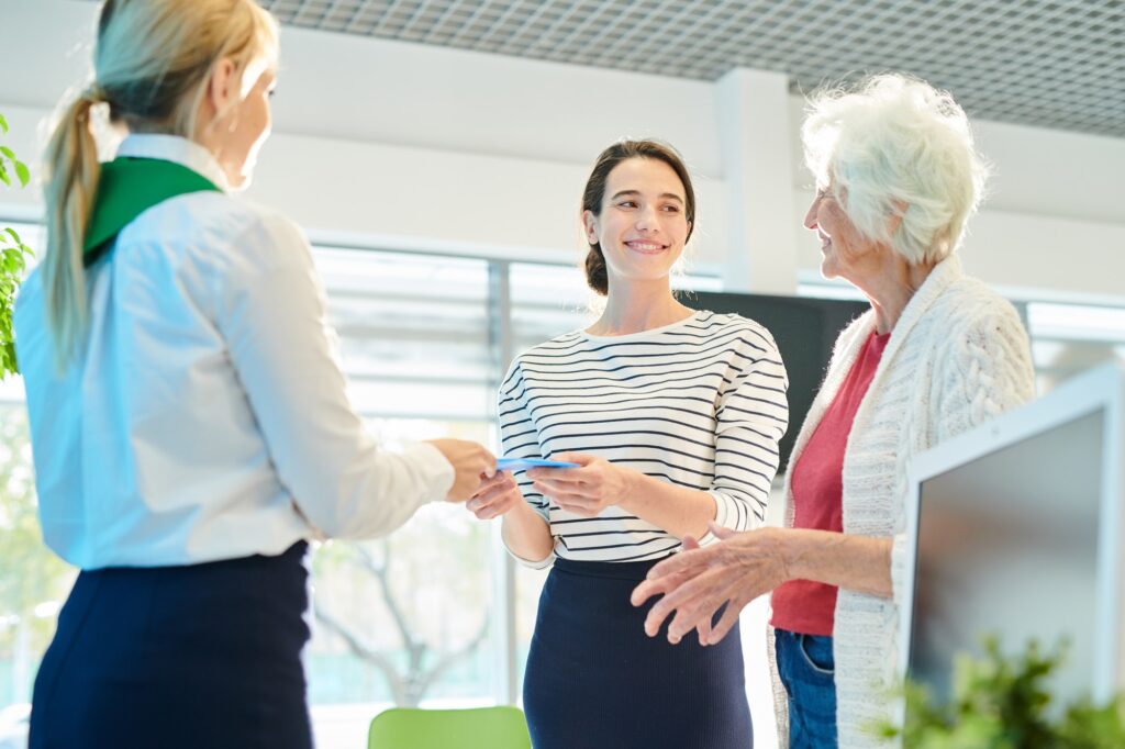 Bank employee issuing documents to young lady with mother