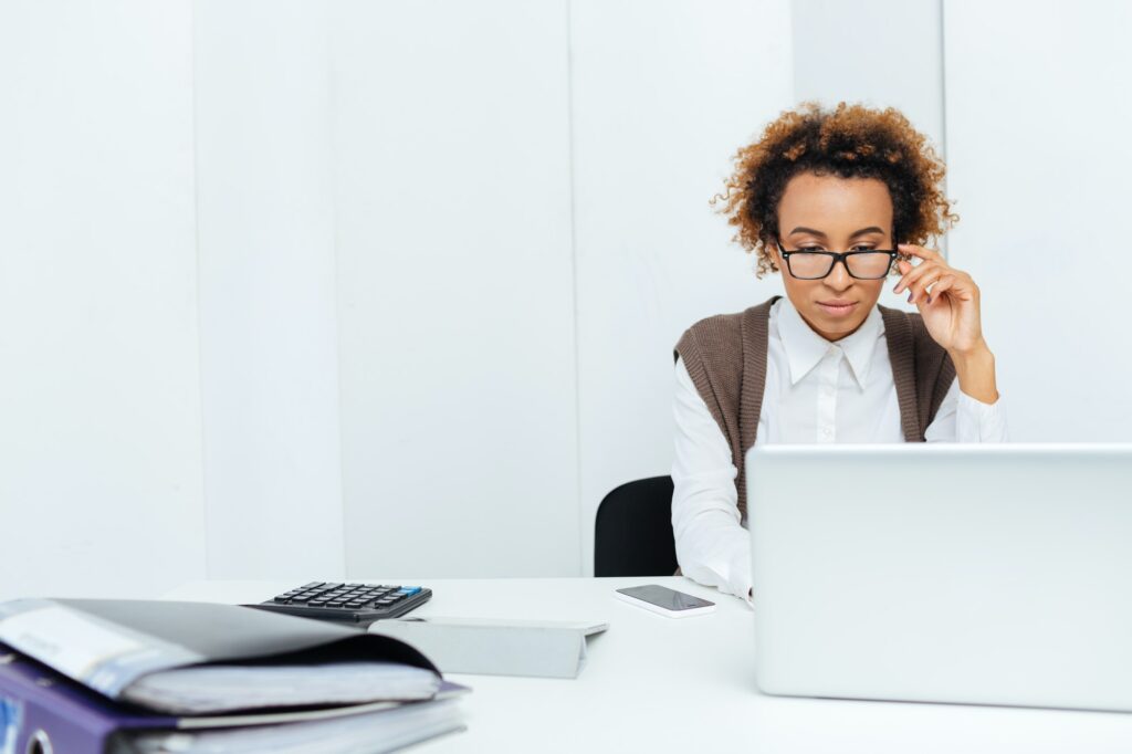 Concentrated african american woman accountant working in office using laptop