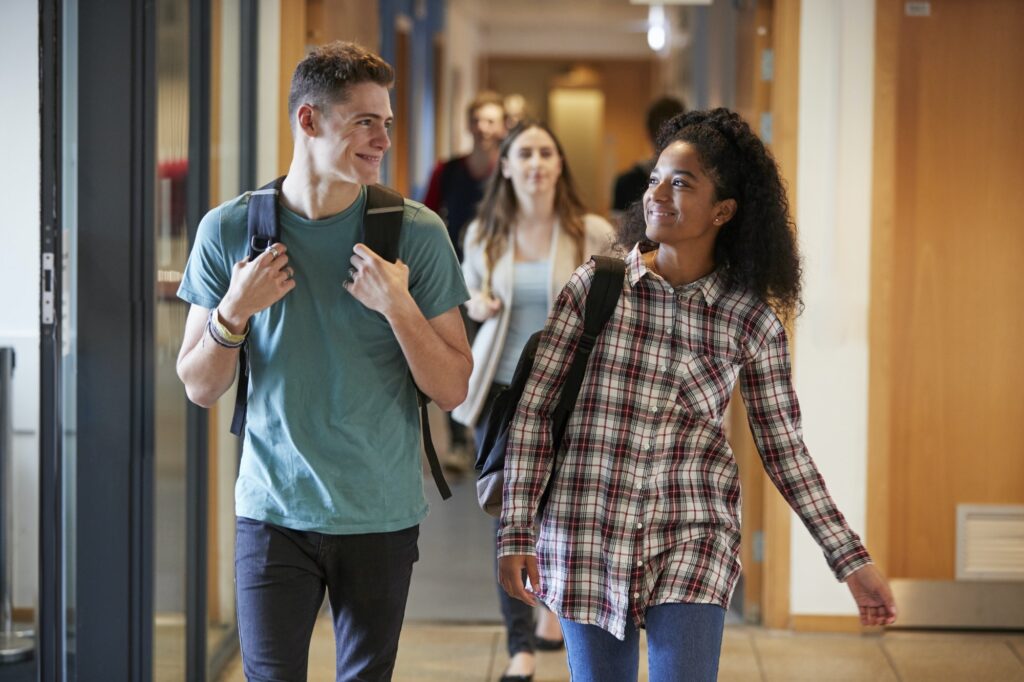 Group Of College Students Walking Through College Corridor