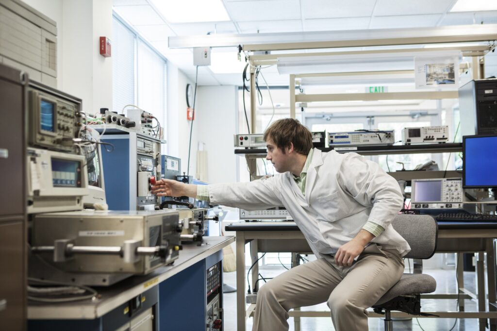 A male caucasian technician sitting at a workbench at a technical research and development site.